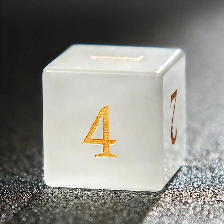 Close-up of a white jade D4 die featuring golden numerals, part of the artisan-crafted pirate dice set.